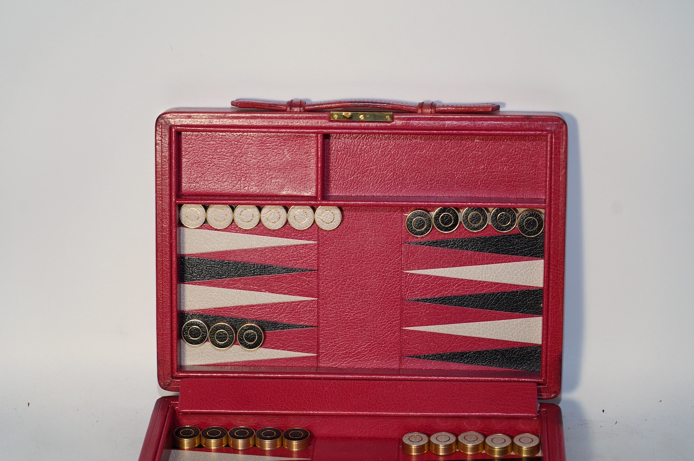 A Geoffrey Parker red leather backgammon set and a black leatherette wrist watch case